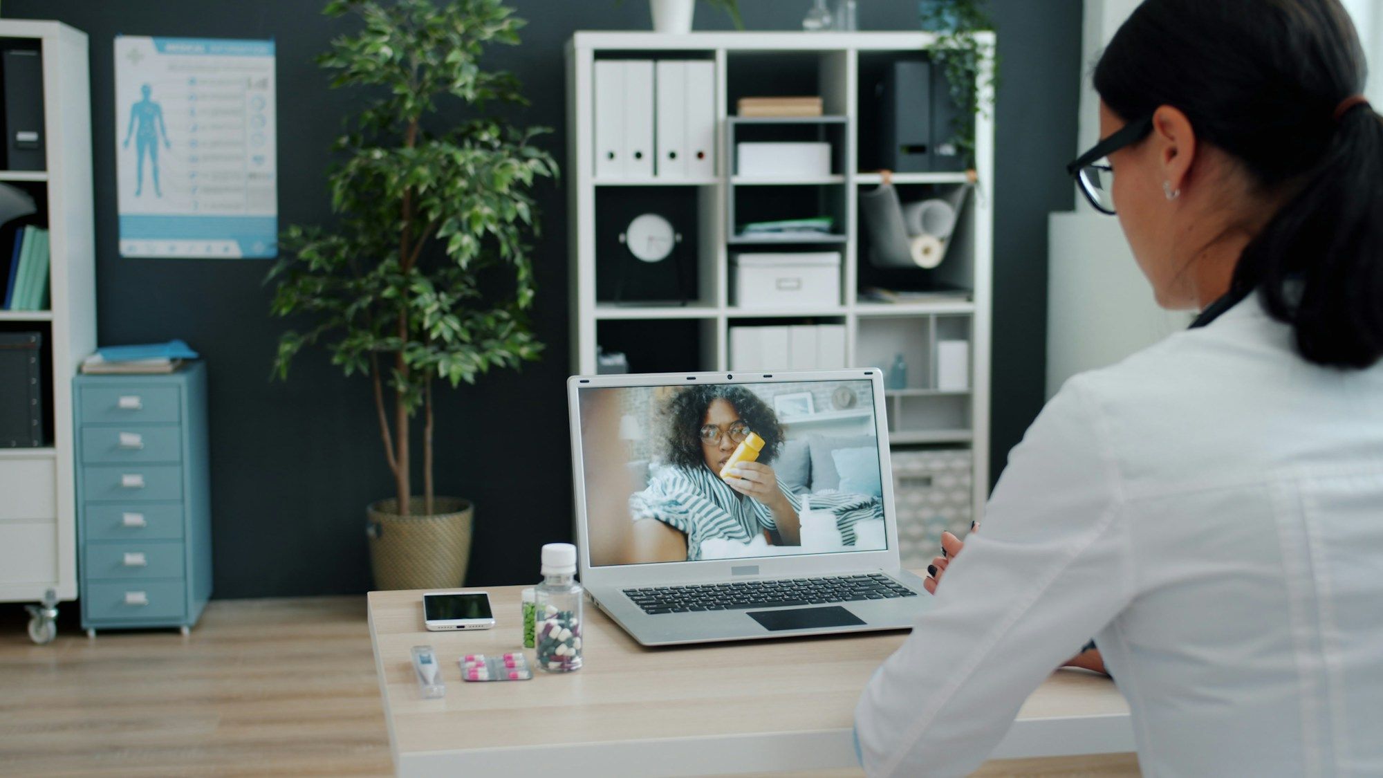 Médica atendiendo a un paciente por videollamada desde su consulta